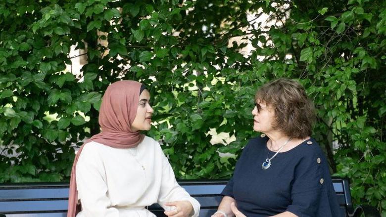 Two women sitting on a bench and talking